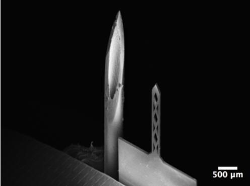 开孔钛基微针（200um宽，50um厚，1500um长）和26G皮下注射针（外径464um）对比的扫描电子显微镜照片